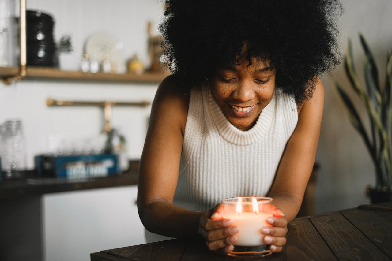about-img A cheerful woman enjoying a fragrant candle indoors, creating a cozy and peaceful atmosphere.