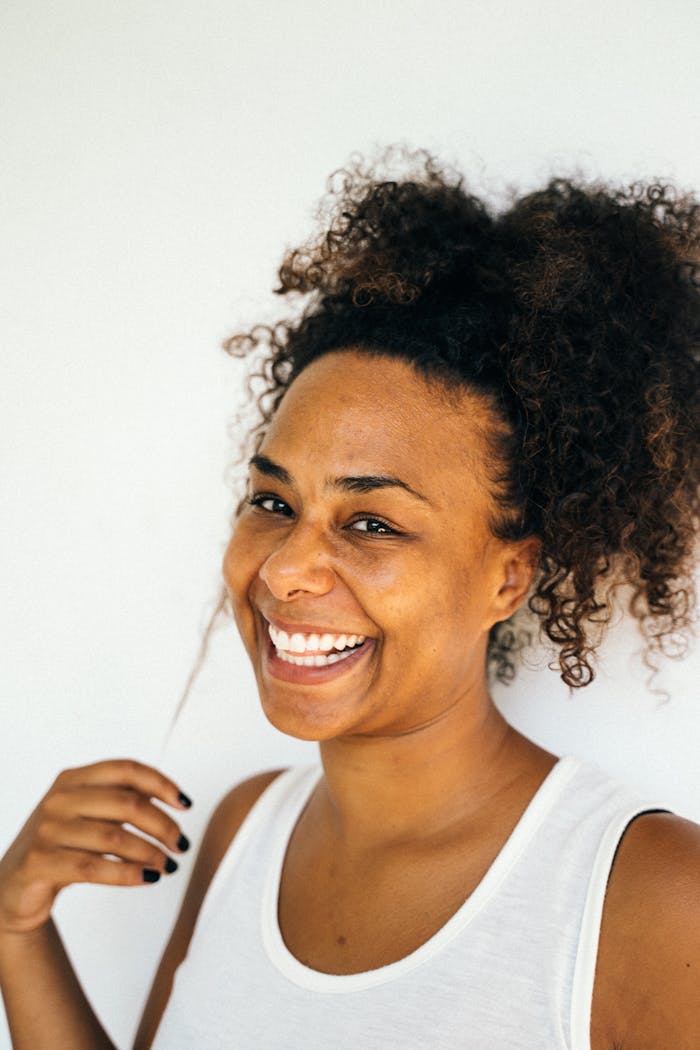 vision Close-up of a joyful African American woman smiling against a plain background.