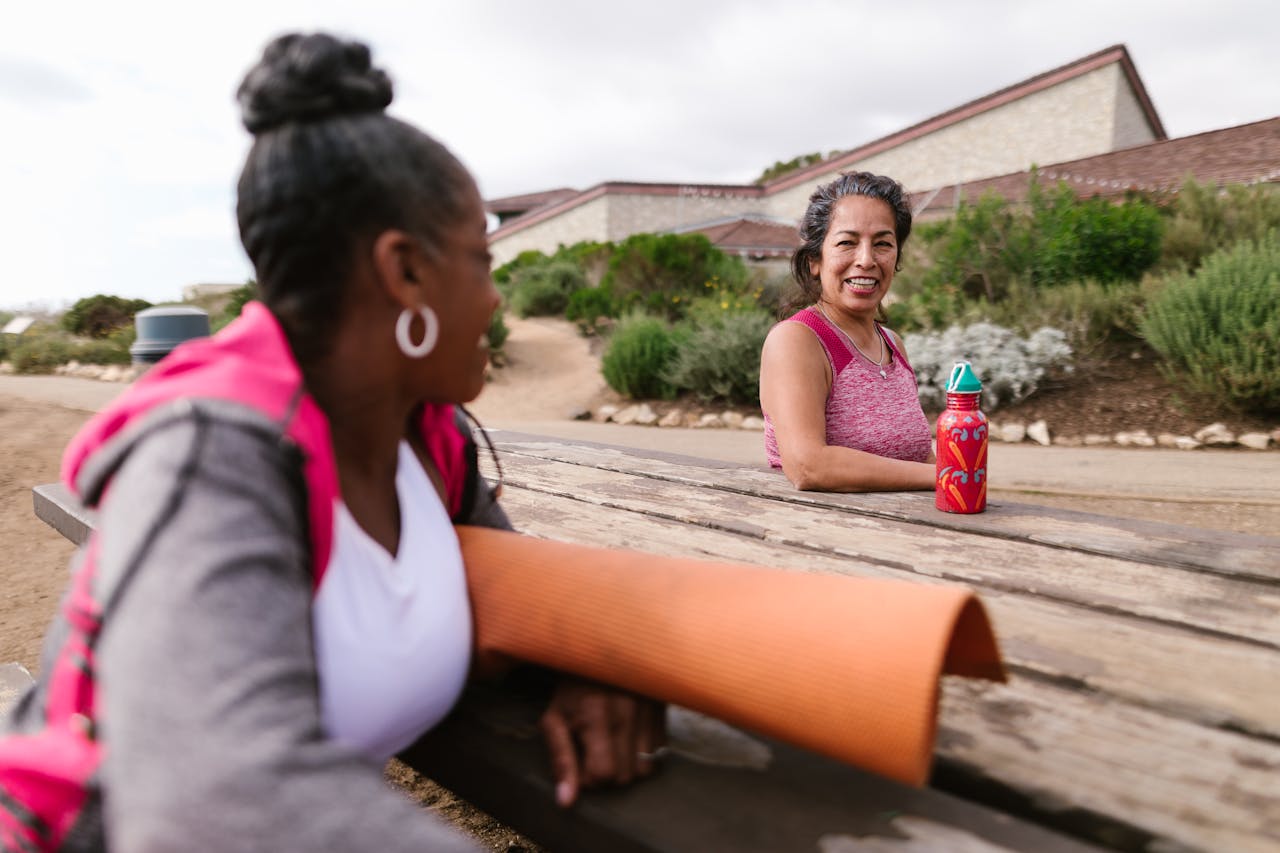 journey-01 Two women enjoying a relaxing day outdoors after yoga with a mat and water bottle.